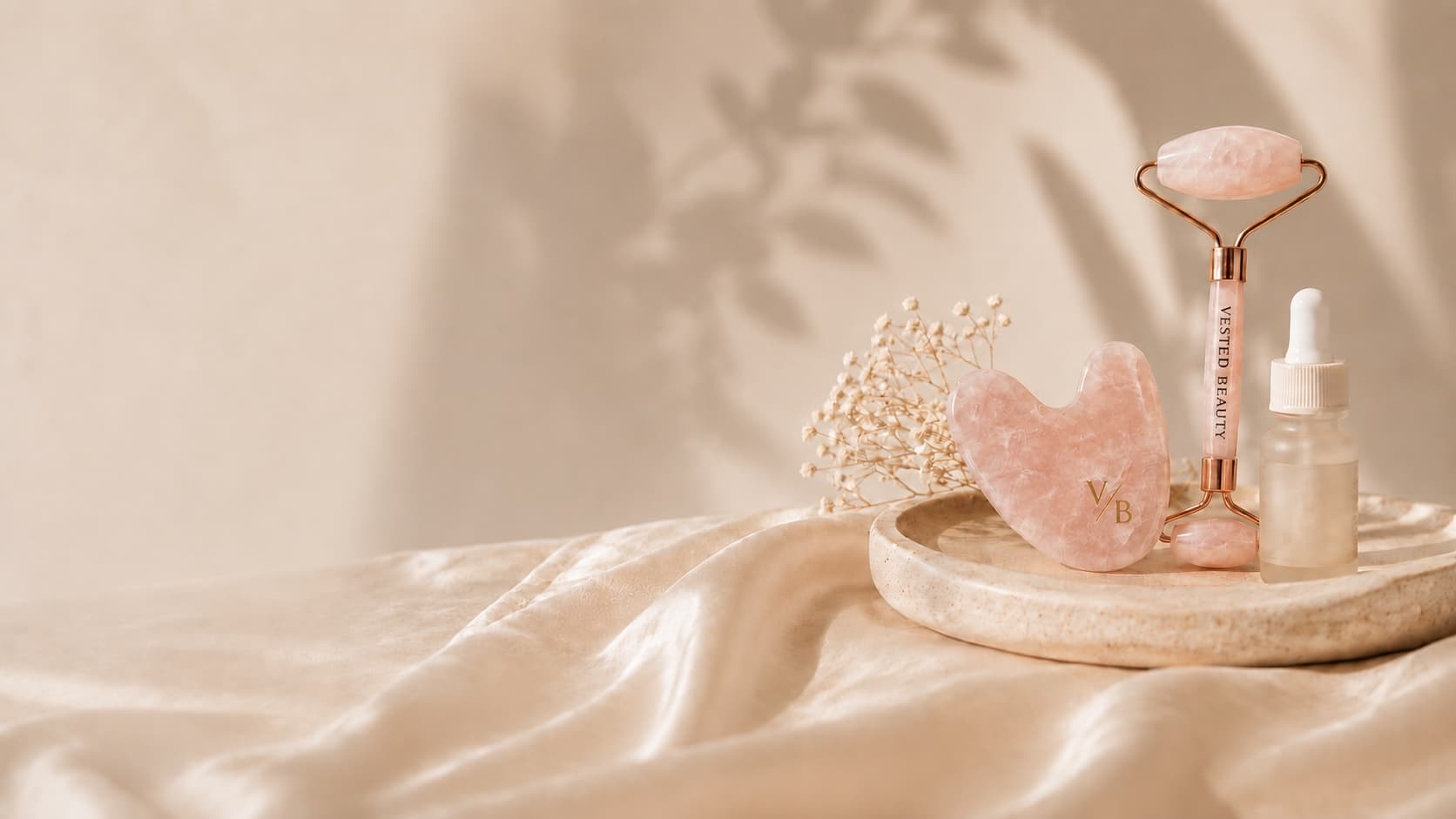 Rose quartz roller, gua sha, and serum on silk